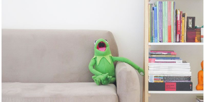 Kermit the frog puppet laughing on a couch